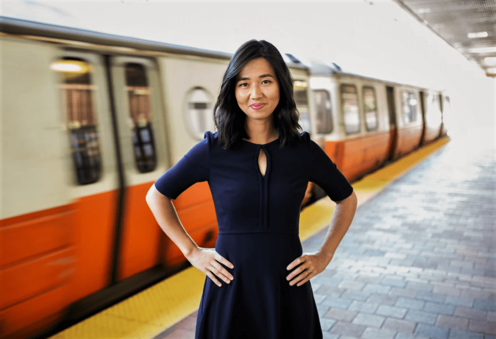 Photo of an Asian woman (Michelle Wu) standing in front of a train.