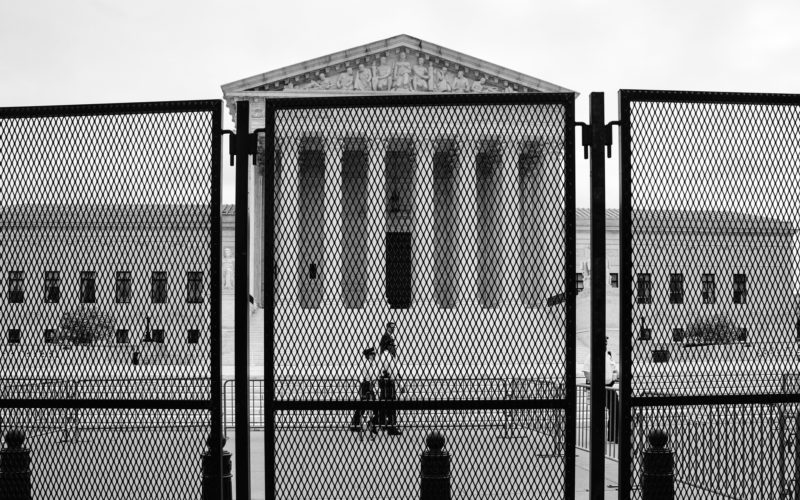 Photo of the Supreme Court entrance with fences surrounding the grounds in response to protests after a leaked ruling striking down abortion rights.