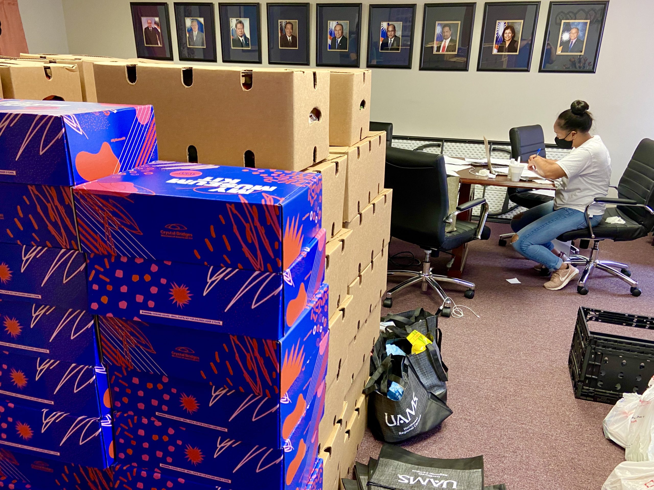 Photo of Marshallese Education Initiative workers putting together PPE and school supplies in a stack of boxes in an office