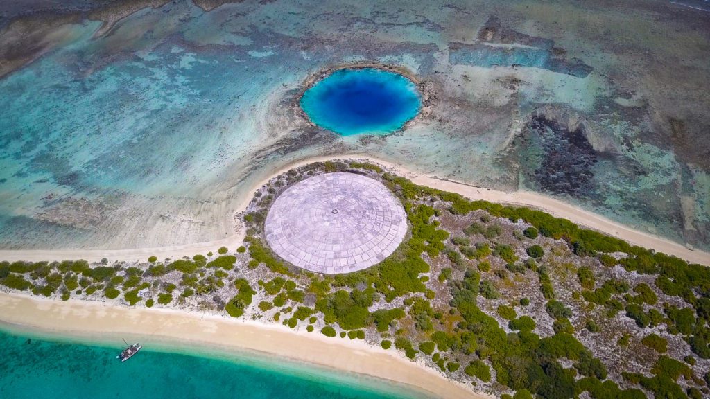 Photo showing a massive dome structure in the middle of the Marshall Islands. The radiation from the dome has had negative effects on Marshallese people's health.