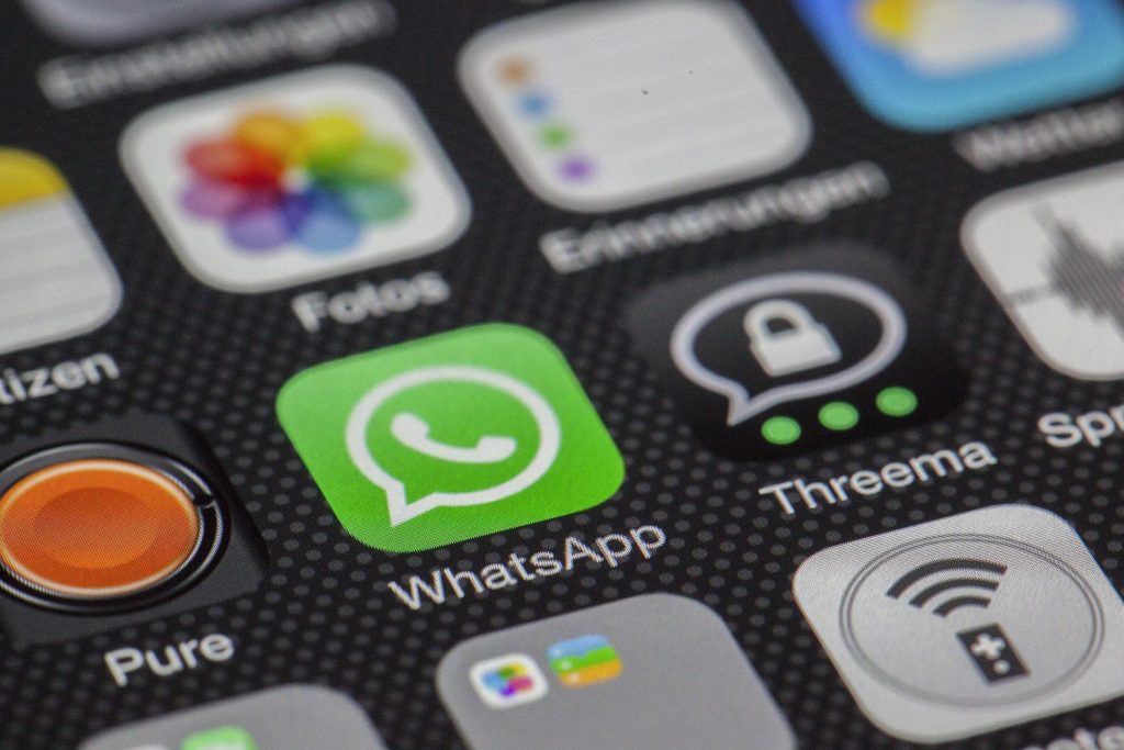 Photo of a phone screen that shows a host of apps. The camera is focused on the bright green icon showing the logo for WhatsApp, which serves as a hub for misinformation.