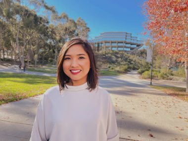 Photo of Kylie Taitano in a white sweater smiling at the camera