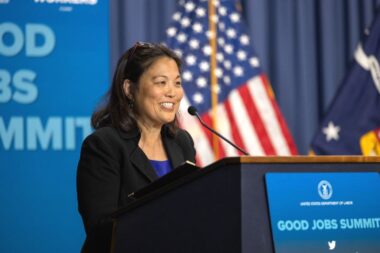 Photo of Julie Su speaking from a podium while smiling
