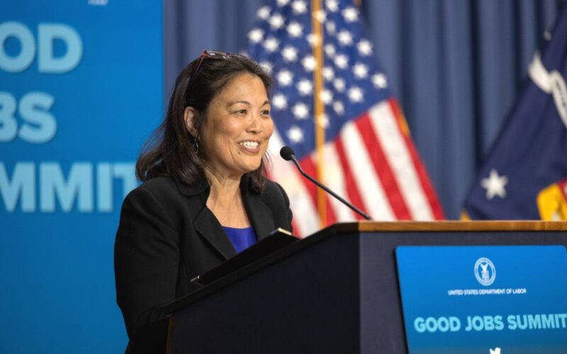 Photo of Julie Su speaking from a podium while smiling