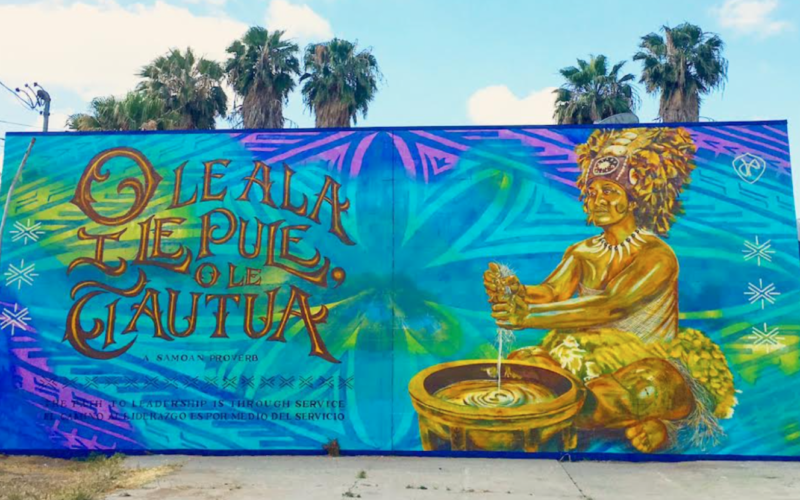 Photo of an art mural showing a Samoan woman participating in a traditional ceremony. The words “O le ala i le pule, o le tautua” are written next to her.