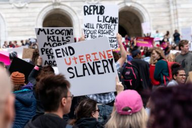 Demonstrators hold up signs including one that says "End Uterine Slavery."