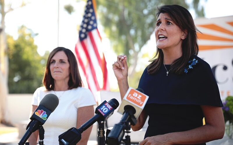 Photo of Nikki Haley speaking into a bundle of different news mics