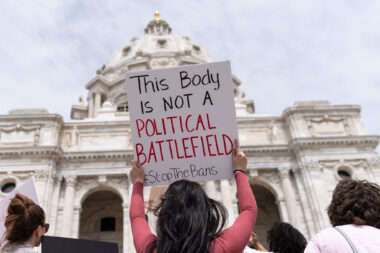 A protester holds a sign that says "This body is not a political battlefield" at an abortion rights rally outside a government building.