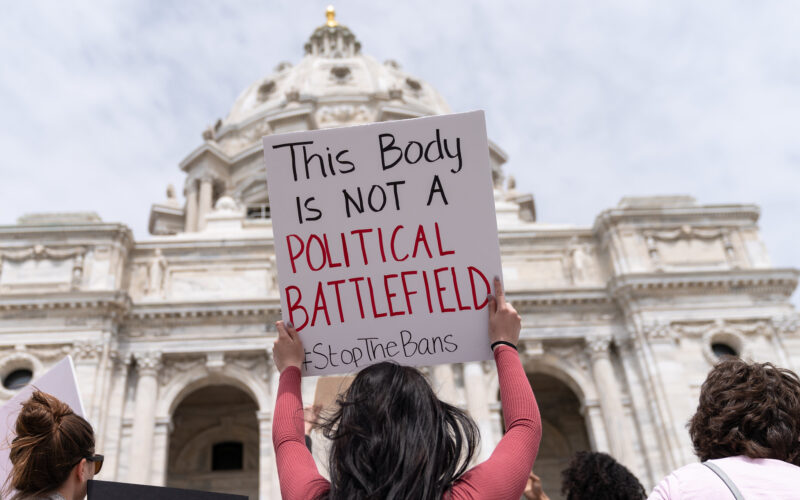 A protester holds a sign that says "This body is not a political battlefield" at an abortion rights rally outside a government building.