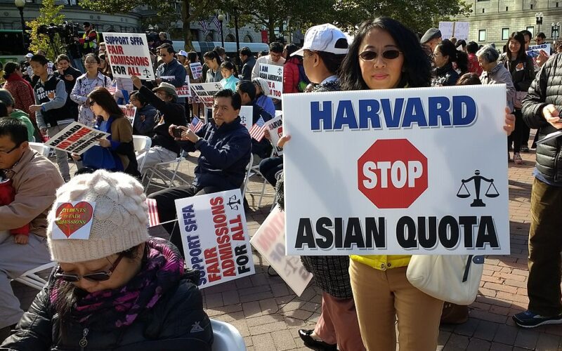 People hold up signs denouncing Harvard’s “Asian quota” at a rally against affirmative action in admissions.