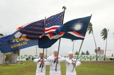 Photo of U.S. naval soldiers holding the U.S. flag and the Marshall Islands flag in a formation