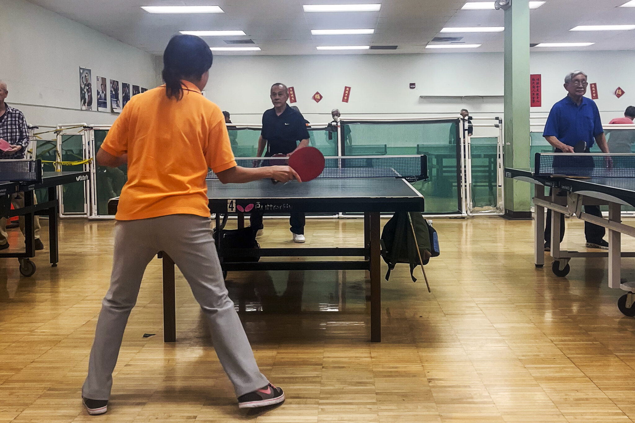 Photo of elders playing table tennis in a large room