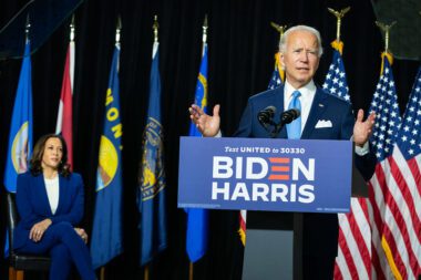 Photo of Joe Biden speaking from a podium as Kamala Harris watches from behind