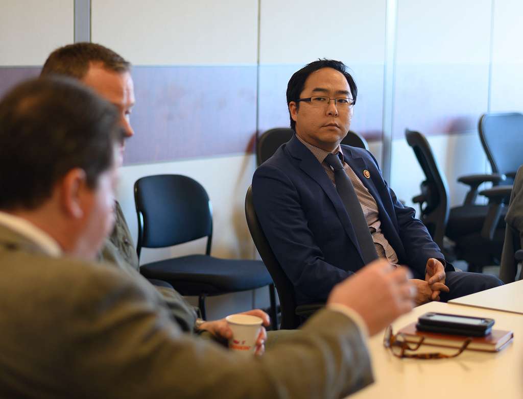 Photo of Andy Kim sitting with military officials