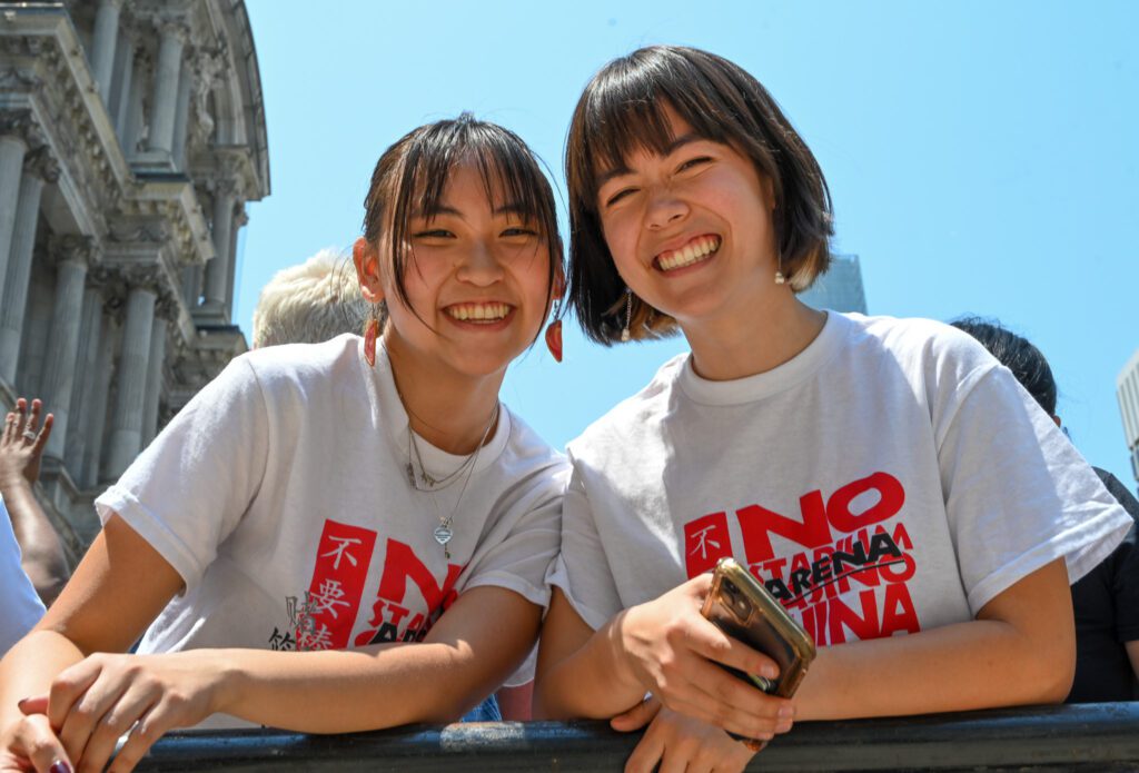 Photo of two activists smiling at the camera while at a demonstration demanding protections for Philadelphia Chinatown