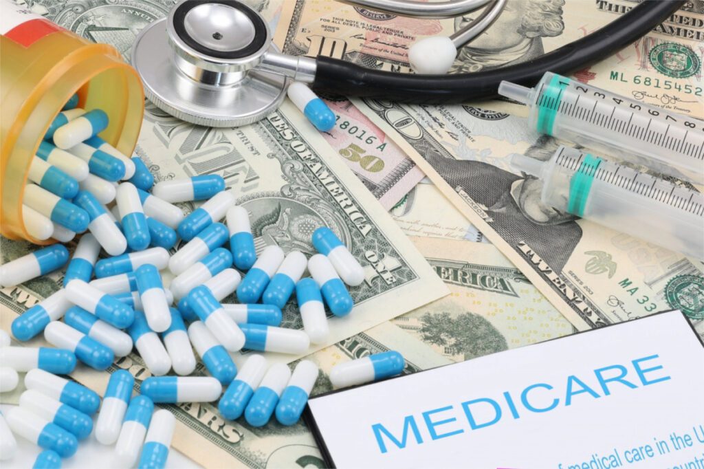 Photo of medication pills splayed on top of dollar bills and a piece of paper that says "Medicare."