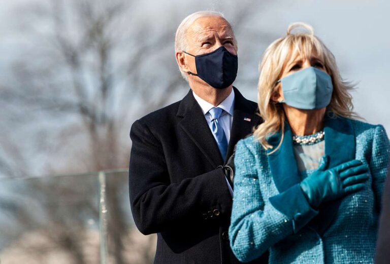Photo of a masked Joe and Jill Biden standing withh their hands over their hearts