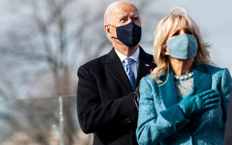 Photo of a masked Joe and Jill Biden standing withh their hands over their hearts