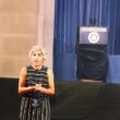 Photo of Kiran Ahuja speaking in front of a stage