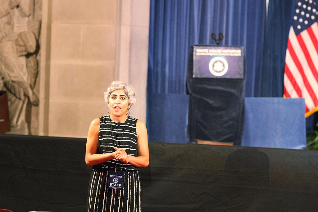 Photo of Kiran Ahuja speaking in front of a stage