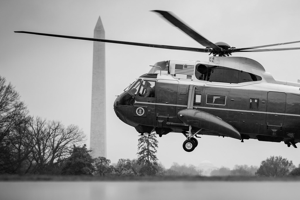 Black and white photo of a helicopter against the backdrop of the Washington Monunment