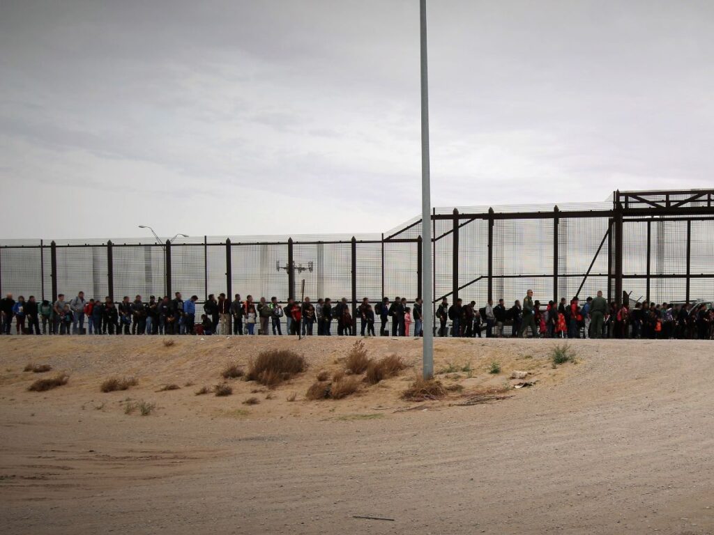 Photo of migrants, including asylum seekers, lining up at a border entry point in a bid for immigration into the U.S.
