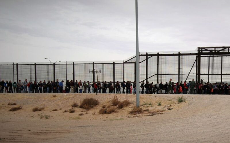 Photo of migrants, including asylum seekers, lining up at a border entry point in a bid for immigration into the U.S.