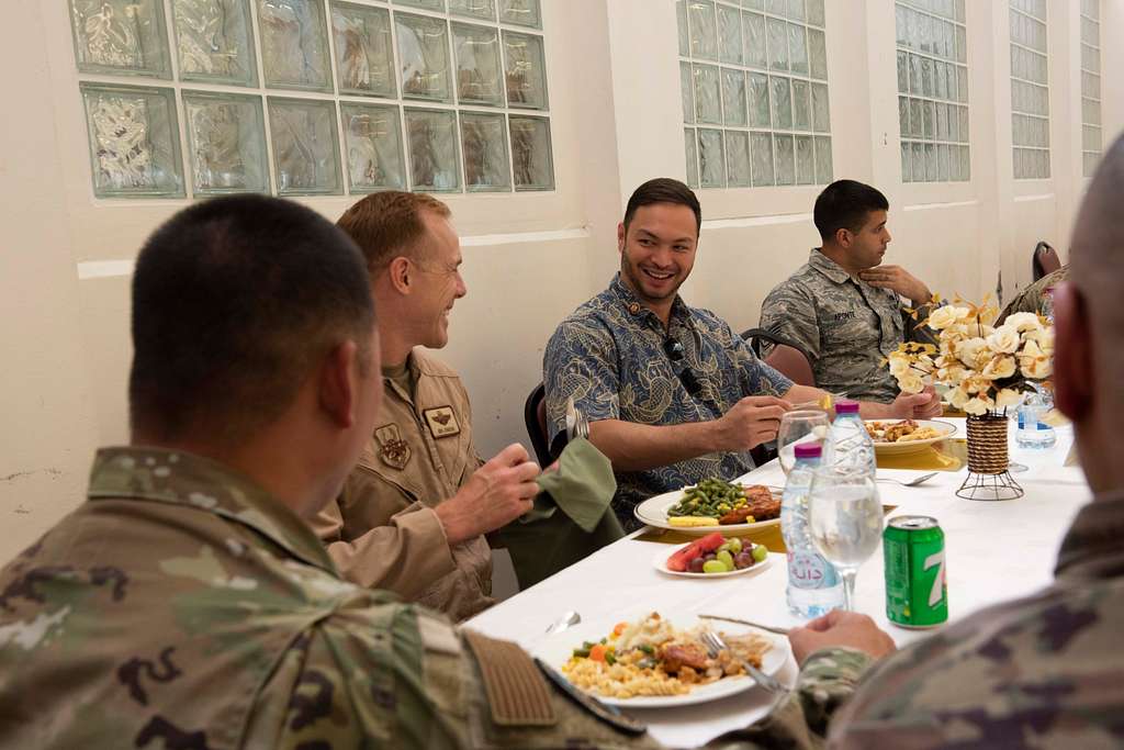 Photo of Michael San Nicolas smiling as he speaks with other soldiers and eats a meal at a long table