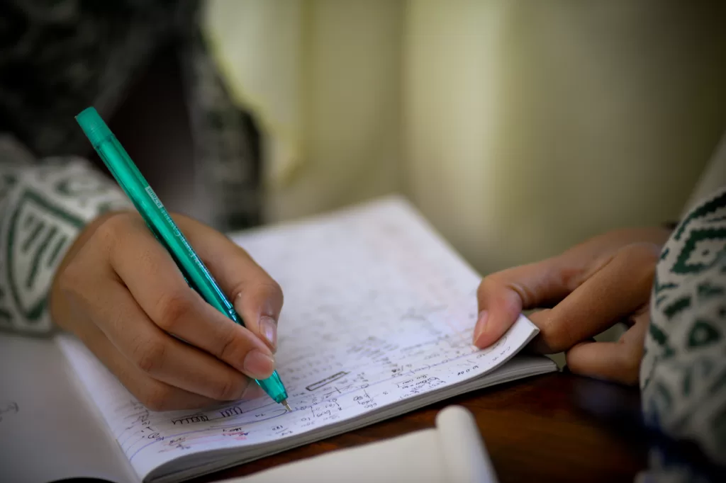Photo of a student writing math equations in a notebook to reflect challenges with ADHD