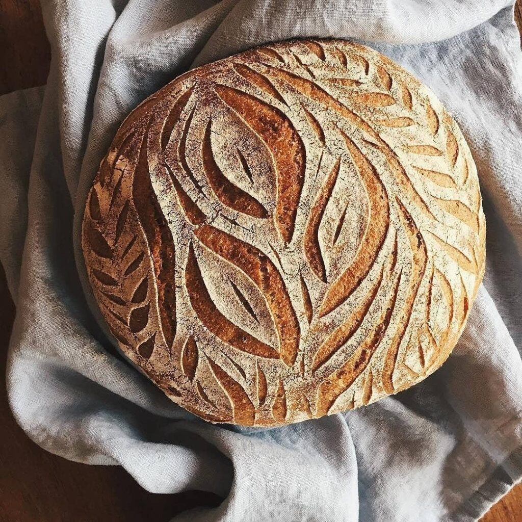 Photo of a round, golden-brown loaf of bread with intricate ridges, created from Mai Nguyen's cultural farming practices.