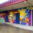 Photo of a colorful mural showing Larry Itliong's portrait on the wall of a library
