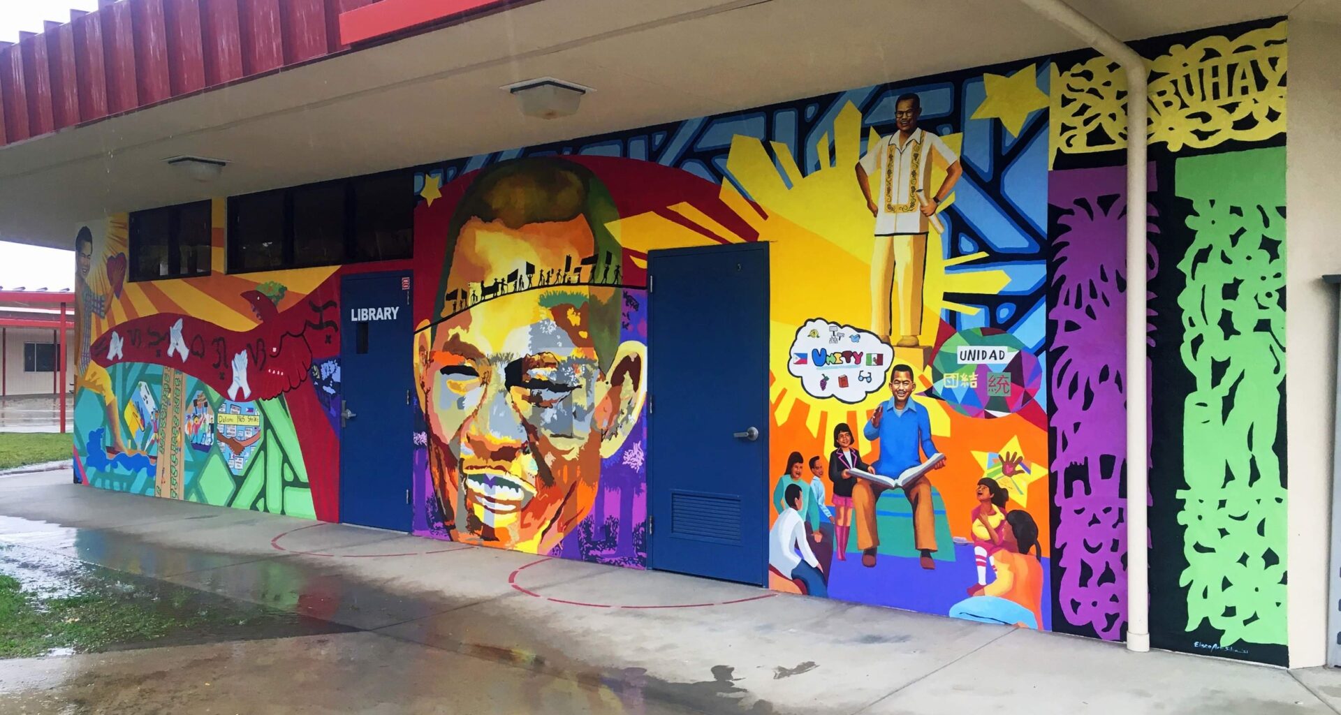 Photo of a colorful mural showing Larry Itliong's portrait on the wall of a library