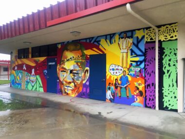 Photo of a colorful mural showing Larry Itliong's portrait on the wall of a library