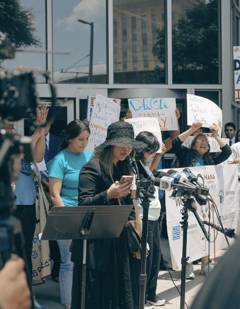 Photo showing Woojung "Diana" Park speaking into microphones at a rally held by the Our City, Our Vote campaign