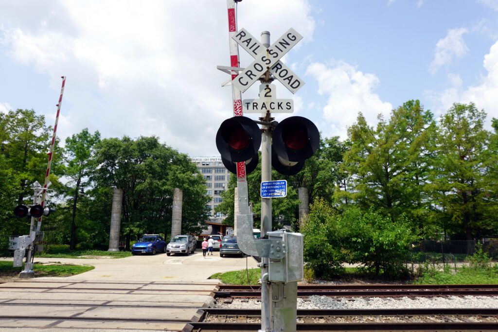 Photo of a railroad crossing at the entrance of an environmental haven filled with green trees