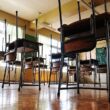 Photo of an empty classroom with chairs placed upside down on top of the desks