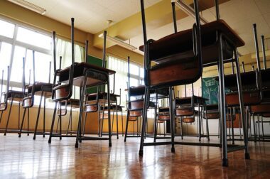 Photo of an empty classroom with chairs placed upside down on top of the desks