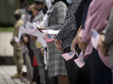 Photo of a naturalization ceremony on Citizenship Day, showing a row of people holding U.S. flags