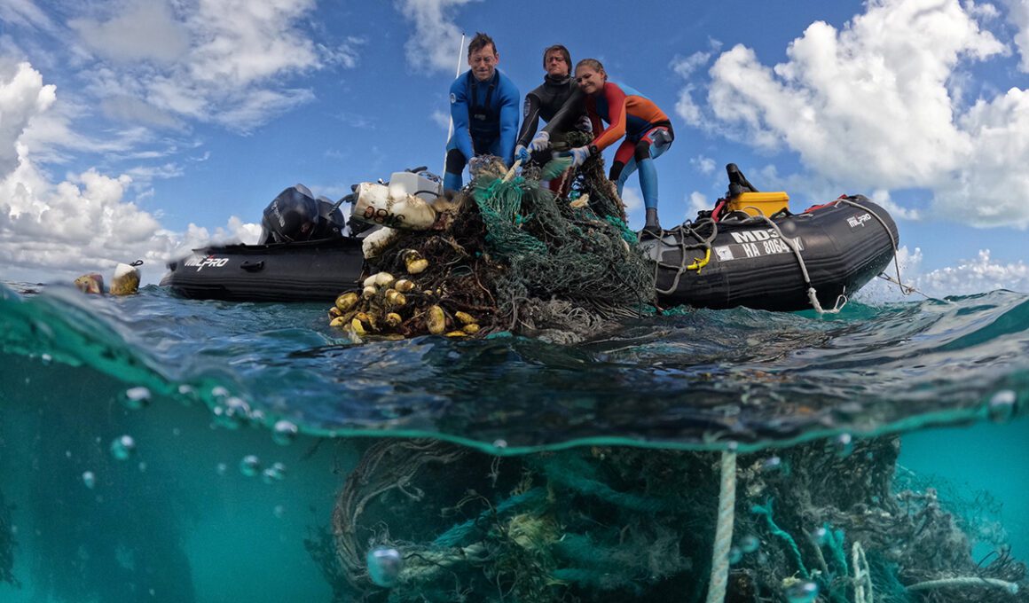 Photo of freedivers hauling in marine debris, including run-down fishing nets, from a boat