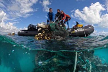 Photo of freedivers hauling in marine debris, including run-down fishing nets, from a boat