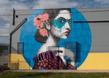 Photo of an art mural depicting an Asian woman wearing a blue eye mask in a Florida neighborhood