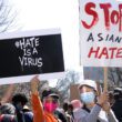 Photo of two protesters holding signs that say "#HateIsAVirus" and "Stop Asian Hate"