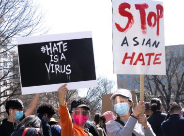 Photo of two protesters holding signs that say "#HateIsAVirus" and "Stop Asian Hate"