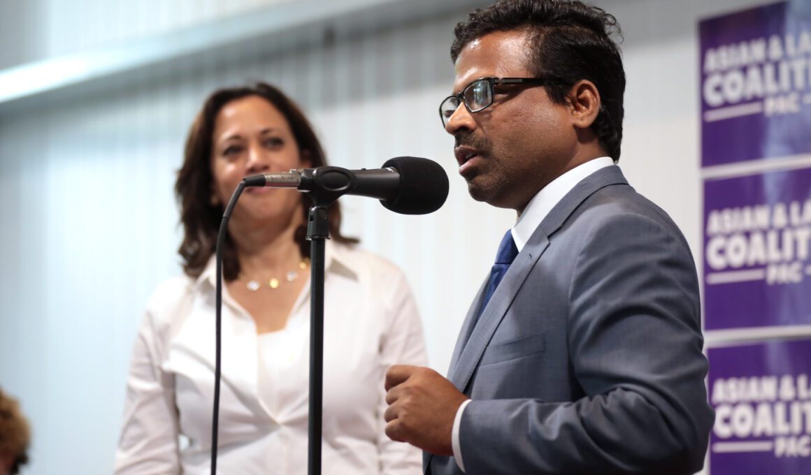Photo of a woman watching a man speak into a microphone at an event in Iowa