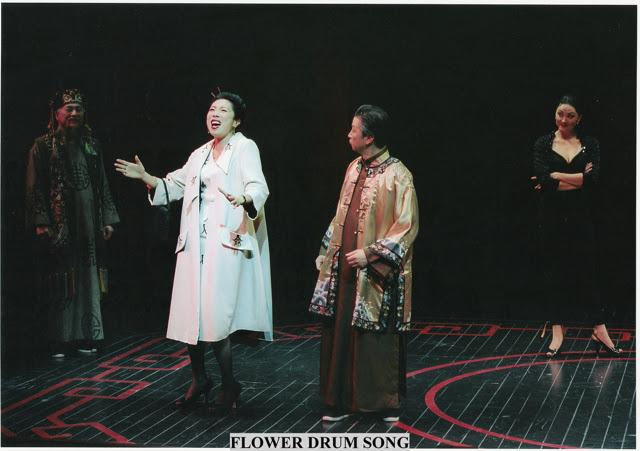 Jodi Long, in a while coat, performs on stage while surrounded by three other actors